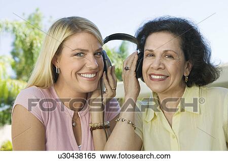 Stock Photography - Mother and Daughter Sharing Headphones. Fotosearch