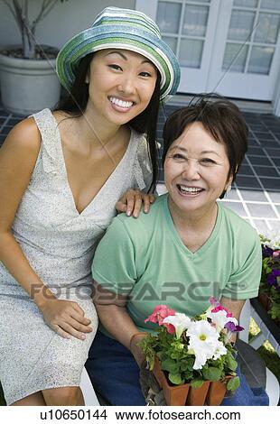 Picture - Mother and daughter with flowers, outdoors, (portrait). Fotosearch
