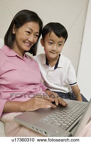 Stock Image - Mother and Son Using Laptop in living room. Fotosearch