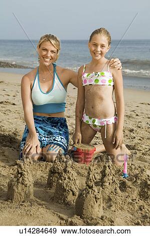 Stock Photo - Mother and Young Daughter Building Sand Castle on Beach. Fotosearch