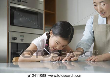 Mother standing at kitchen counter, Pointing at Daughter's Drawing View Large Photo Image Stock Photo - Mother standing at kitchen counter, Pointing at Daughter's Drawing. Fotosearch