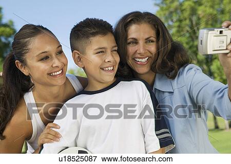 Stock Photo - Mother using digital camera, photographing self with daughter and son (13-15).. Fotosearch