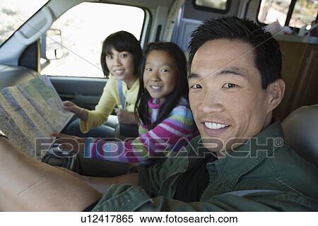 Stock Photography - Parents with daughter looking at map in RV. Fotosearch