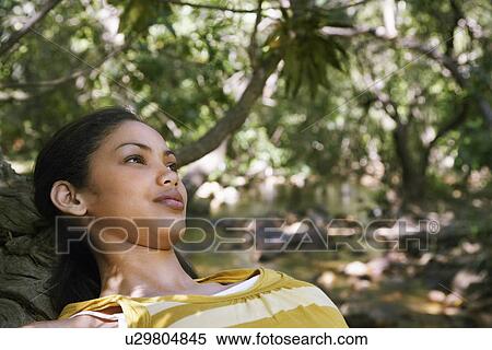 Stock Photography - Portrait of teenage girl (16-17 years) relaxing in forest, smiling. Fotosearch