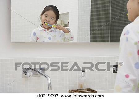 Stock Photo - Reflection of Young Girl in pyjamas Brushing Her Teeth. Fotosearch