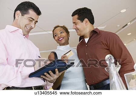Salesman Calculating Purchase Amount of couple in furniture store, low angle view View Large Photo Image Stock Photography - Salesman Calculating Purchase Amount of couple in furniture store, low angle view. Fotosearch