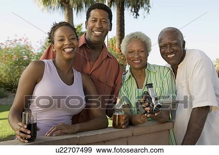 Stock Photo - Senior couple and mid-adult couple, senior woman holding camcorder, portrait.. Fotosearch