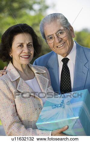 Stock Image - Senior couple Holding present outside, portrait. Fotosearch