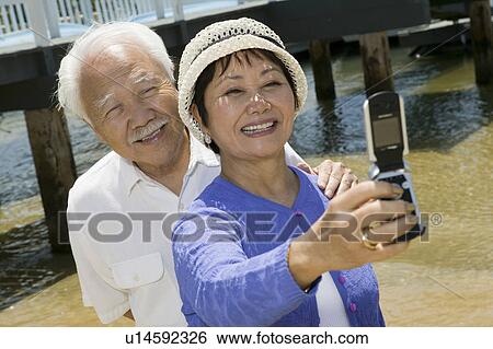 Senior couple photographing themselves by pier View Large Photo Image Stock Photograph - Senior couple photographing themselves by pier. Fotosearch