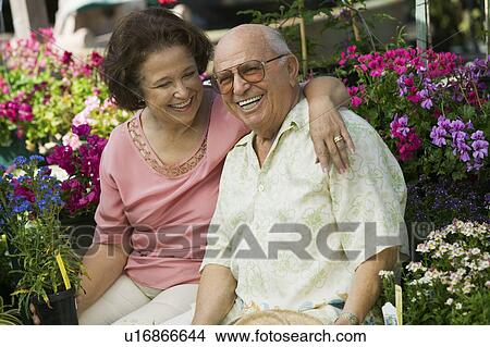 Senior Couple sitting among flowers at plant nursery, portrait View Large Photo Image Picture - Senior Couple sitting among flowers at plant nursery, portrait. Fotosearch
