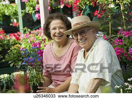 Senior Couple sitting among flowers at plant nursery, portrait View Large Photo Image Stock Image - Senior Couple sitting among flowers at plant nursery, portrait. Fotosearch