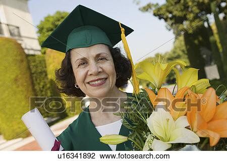 Stock Image - Senior Graduate holding diploma and flowers outside, portrait. Fotosearch