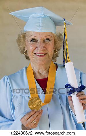 Stock Image - Senior graduate holding diploma and medal outside, portrait. Fotosearch