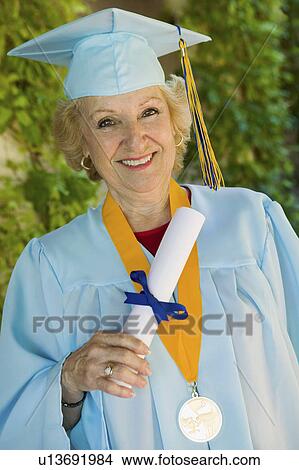 Senior graduate holding diploma outside, portrait View Large Photo Image Picture - Senior graduate holding diploma outside, portrait. Fotosearch