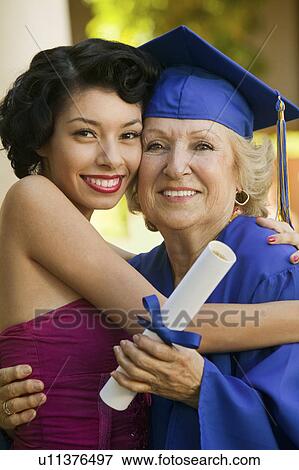 Stock Photo - Senior graduate hugging granddaughter outside. Fotosearch