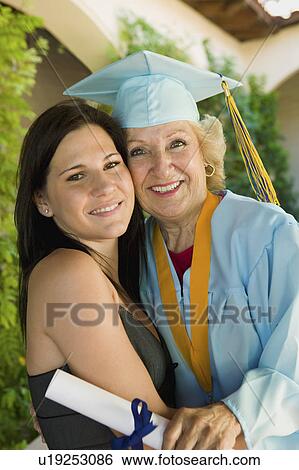 Stock Photograph - Senior graduate hugging granddaughter outside, portrait. Fotosearch