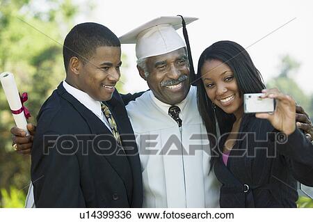 Stock Photograph - Senior graduate taking picture with grandchildren outside. Fotosearch