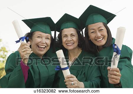 Stock Image - Senior Graduates hoisting diplomas outside, portrait. Fotosearch
