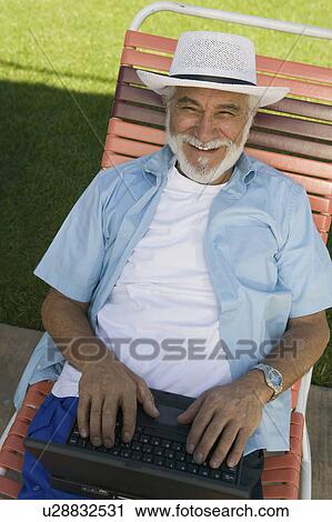 Senior Man sitting on Lawn Chair Using Laptop, elevated view portrait. View Large Photo Image Stock Image - Senior Man sitting on Lawn Chair Using Laptop, elevated view portrait.. Fotosearch