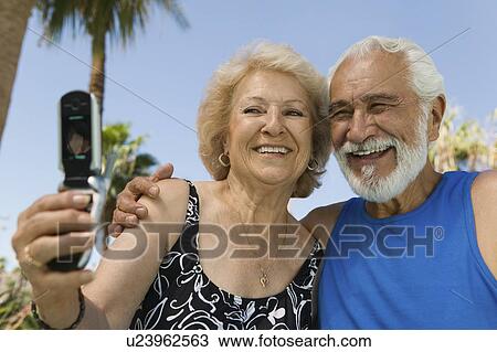Senior woman using mobile phone, photographing self with husband outdoors. View Large Photo Image Stock Image - Senior woman using mobile phone, photographing self with husband outdoors.. Fotosearch