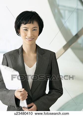 Smiling businesswoman standing, holding clipboard View Large Photo Image Stock Image - Smiling businesswoman standing, holding clipboard. Fotosearch