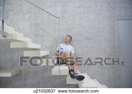Smiling mid-adult man sitting on staircase, holding bottle of water View Large Photo Image Stock Photo - Smiling mid-adult man sitting on staircase, holding bottle of water. Fotosearch