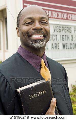 Stock Photo - Smiling Preacher in Front of Church, portrait. Fotosearch