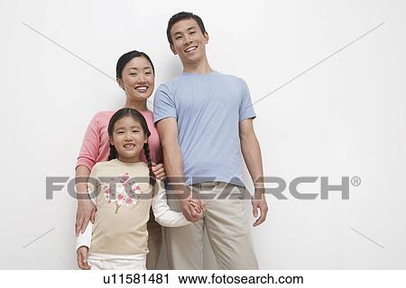 Stock Image - Smiling Young couple and daughter family portrait, low angle view. Fotosearch