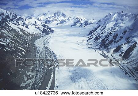 Stock Photograph - Snowfield in valley between snow-covered mountains. Fotosearch