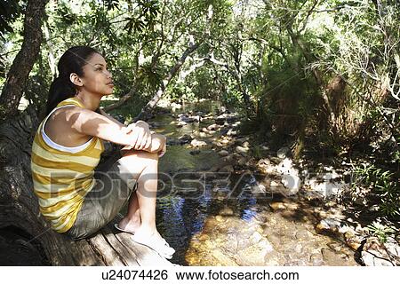 Teenage girl (16-17 years) sitting on tree trunk by stream in forest View Large Photo Image Stock Photograph - Teenage girl (16-17 years) sitting on tree trunk by stream in forest. Fotosearch