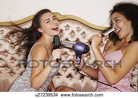 Teenage Girls playing with brushes and hair dryer at slumber party View Large Photo Image Picture - Teenage Girls playing with brushes and hair dryer at slumber party. Fotosearch
