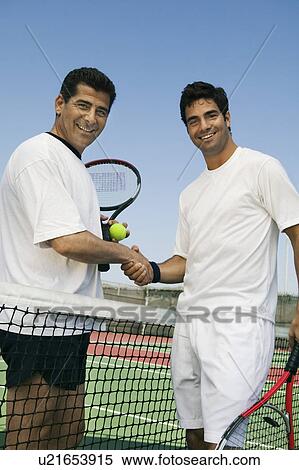 Stock Photography - Tennis Players shaking hands over net on court, portrait. Fotosearch