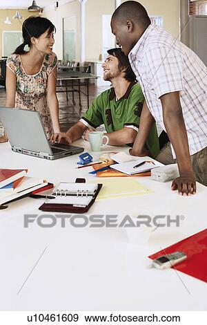 Three office workers around laptop, smiling. View Large Photo Image Stock Photo - Three office workers around laptop, smiling.. Fotosearch