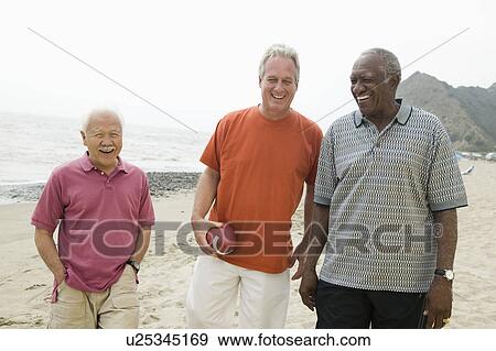 Stock Photo - Three senior men walking on beach. Fotosearch
