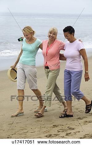 Stock Image - Three women walking on beach. Fotosearch