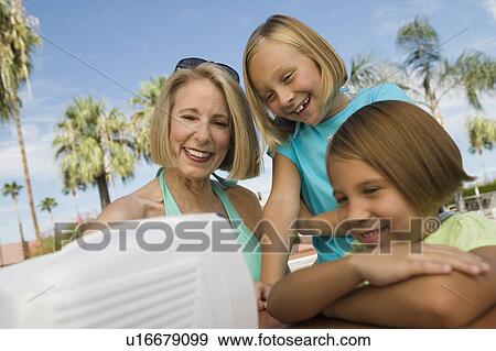 Two girls (7-9) and grandmother watching portable television outdoors. View Large Photo Image Stock Photo - Two girls (7-9) and grandmother watching portable television outdoors.. Fotosearch