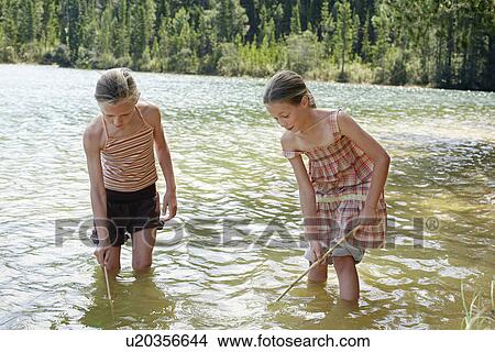 Two girls (7-9) standing in lake, playing. View Large Photo Image Picture - Two girls (7-9) standing in lake, playing.. Fotosearch