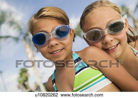 Stock Image - Two girls (7-9) wearing swim goggles, portrait.. Fotosearch
