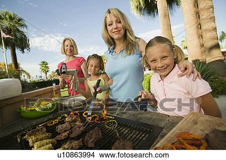 Two girls (7-9) with family at outdoor barbecue, portrait. View Large Photo Image Picture - Two girls (7-9) with family at outdoor barbecue, portrait.. Fotosearch