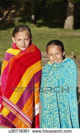 Stock Image - Two Girls (7-9) wrapped in towels, outdoors.. Fotosearch
