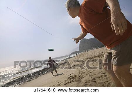 Two men playing with flying disc on beach View Large Photo Image Stock Image - Two men playing with flying disc on beach. Fotosearch