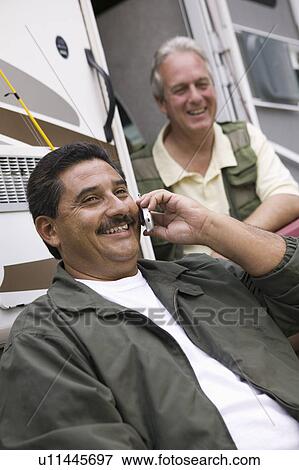 Stock Photo - Two middle-aged man sitting beside caravan. Fotosearch