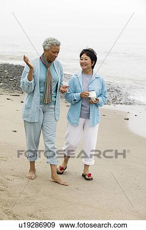 Stock Photo - Two middle-aged women talking on beach. Fotosearch