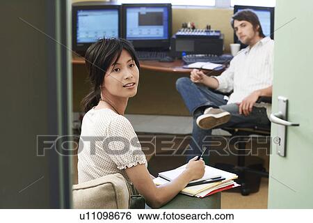 Stock Photograph - Two Office workers having meeting, woman taking notes.. Fotosearch