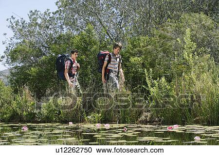 Two teenage boys (16-17 years) walking by lake with backpacks View Large Photo Image Stock Image - Two teenage boys (16-17 years) walking by lake with backpacks. Fotosearch