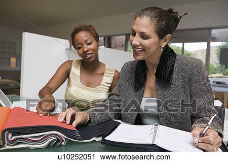 Two women with laptop and organizer examining fabric swatches View Large Photo Image Stock Image - Two women with laptop and organizer examining fabric swatches. Fotosearch