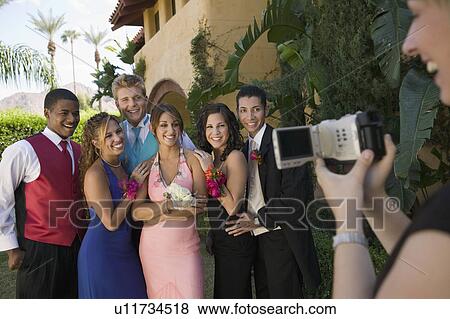 Stock Photo - Well-dressed teenagers posing for video camera outside school dance. Fotosearch
