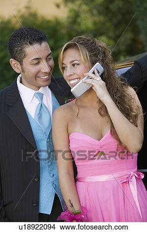 Picture - Well-dressed young couple using cell phone outside. Fotosearch