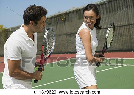 Stock Photo - Woman and male tennis instructor practising racket control on tennis court. Fotosearch