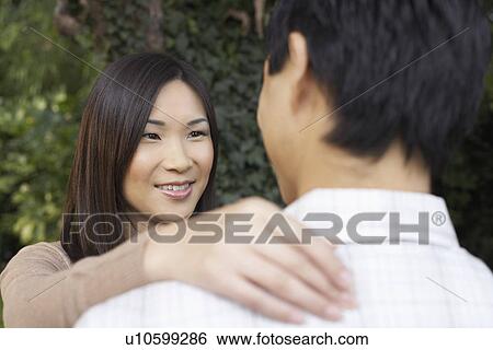 Woman and man standing outside Looking at each other, hand on shoulder View Large Photo Image Stock Photograph - Woman and man standing outside Looking at each other, hand on shoulder. Fotosearch